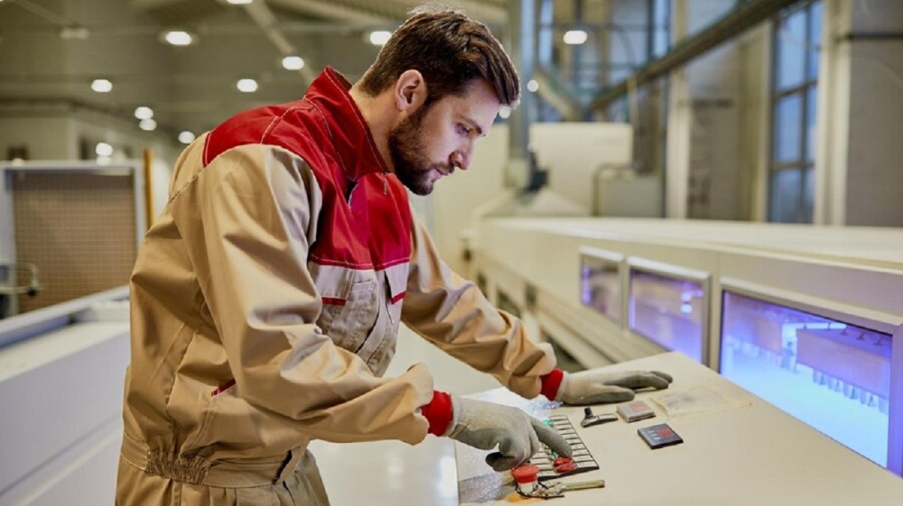 рабочий запускает автоматизированную машину